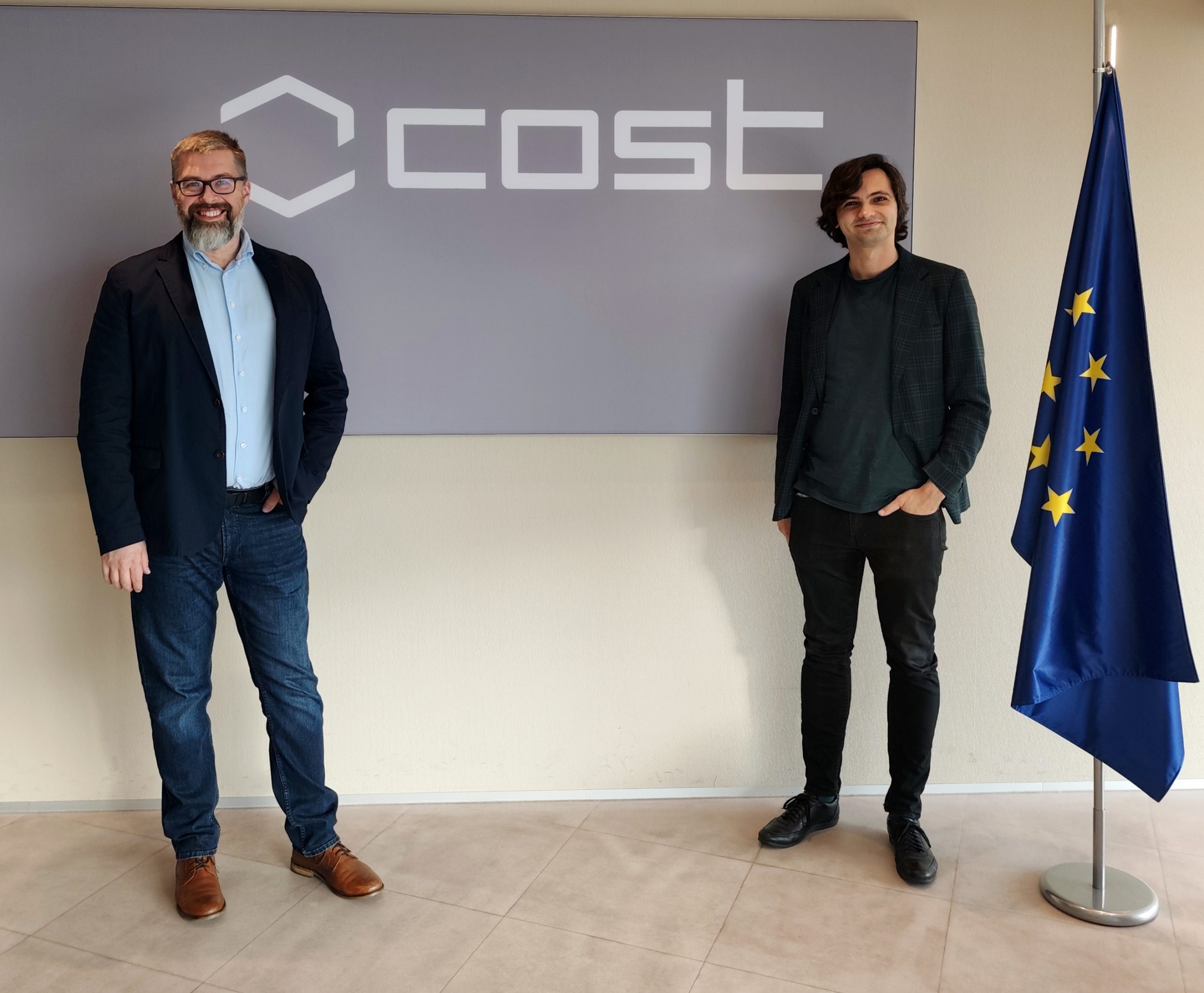 Łukasz Nazarko i Michał Nadziak stoją przy logotypie COST